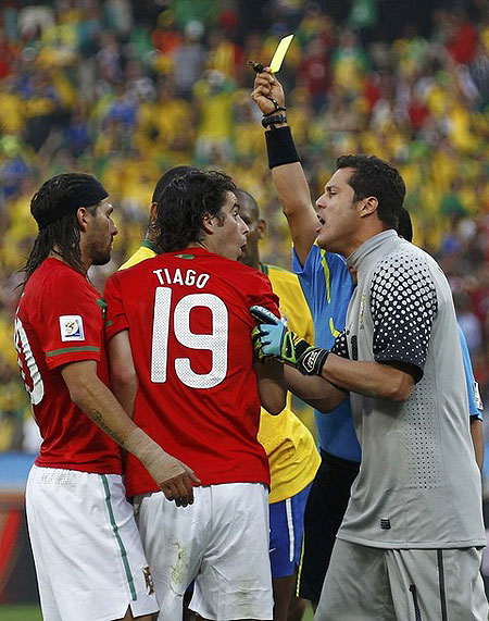 Referee Benito Archindia of Mexico shows the yellow card to Portugal's Tiago (C) as Brazil's goalkeeper Julio Cesar (R) argues during a 2010 World Cup Group G soccer match at Moses Mabhida stadium in Durban June 25, 2010.